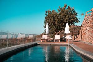 una piscina con 2 sillas y sombrillas en Kea Village Suites & Villas, en Ioulida