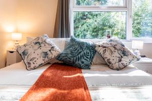 um quarto com uma cama com almofadas e uma janela em MPL Apartments - Malden Road Serviced Accommodation em Watford