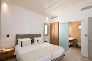 1 dormitorio con 1 cama blanca grande y baño en Island Mykonos Suites, en Mykonos ciudad