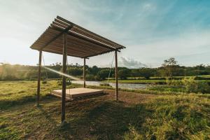 une balançoire en bois dans un champ à côté d'une rivière dans l'établissement Glamping Entre Rios, à Calarcá