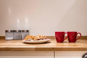 a plate of croissants and two cups on a counter at MPL Apartments - Queens Broadway F4 in Watford