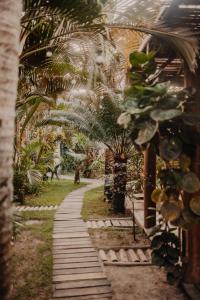 a walkway in a garden with palm trees at Onda´s Caraíva in Caraíva