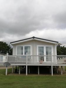 a house with a large porch with a white deck at Hawthorn Hot tub Lodge Northumberland in Newton on the Moor