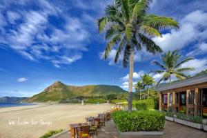 a beach with chairs and palm trees and a building at Hotel Hương Đào in Con Dao