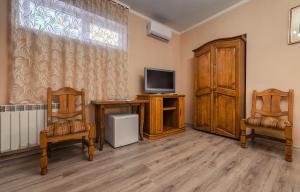 een woonkamer met 2 stoelen en een televisie bij Готель «Вишневий Сад» in Mukacheve