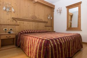 a bedroom with a bed and a wooden wall at Hotel Alpi - Asiago in Asiago