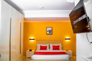 a bedroom with a bed with red pillows and a flat screen tv at RÉSIDENCE DOLCE VITA - BONANJO in Douala