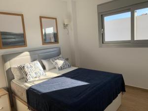 a bedroom with a bed with a blue blanket and a window at Apartamento con solarium Villa Amalia in Torrevieja