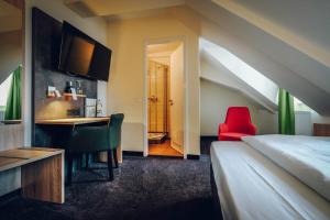 Schlafzimmer mit einem Bett, einem Schreibtisch und einem roten Stuhl in der Unterkunft Hotel Europa in Bamberg