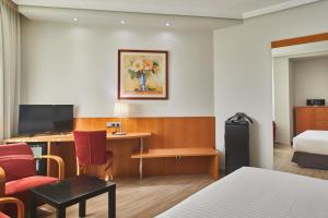 a hotel room with a bed, chair, desk and a tv at Silken Luis de León in León