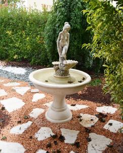 Una estatua de una chica sentada sobre una fuente. en Casa Nives, en San Pietro in Casale