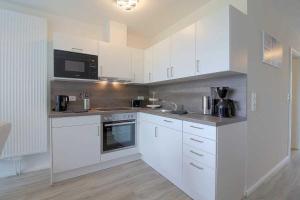 eine Küche mit weißen Schränken und einer Mikrowelle in der Unterkunft KW4b Haus Cati in Dorum Neufeld