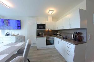 eine Küche mit weißen Schränken, einem Tisch und einem Esszimmer in der Unterkunft KW4b Haus Cati in Dorum Neufeld