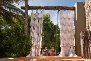 a group of people sitting on a bench under an umbrella at Casa Malca in Tulum