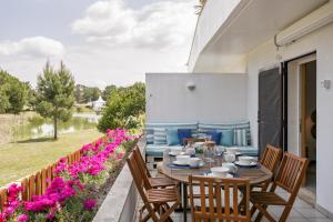 um pátio com uma mesa, cadeiras e flores em Casa de Férias - Troia Terrace Lake & Pool - Soltroia Comporta Aluguer em Tróia