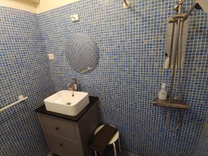ein blau gefliestes Bad mit einem Waschbecken und einem Spiegel in der Unterkunft Charmante maison arlésienne à l'ombre des Arènes, de 2 à 5p in Arles