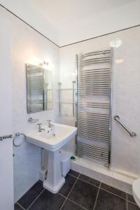 La salle de bains blanche est pourvue d'un lavabo et d'une douche. dans l'établissement Beach House - Aldeburgh Coastal Cottages, à Aldeburgh