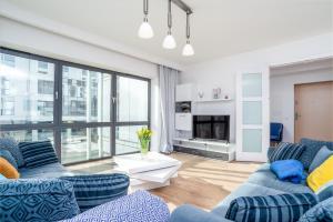 salon z 2 niebieskimi kanapami i dużym oknem w obiekcie Baltiq Plaza Gdynia w mieście Gdynia