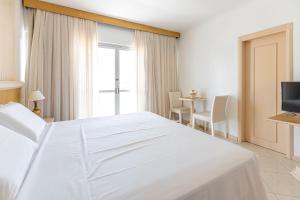 Un dormitorio con una gran cama blanca y una mesa en Hotel dos Açores, en Balneário Camboriú
