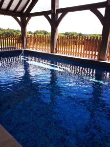 a swimming pool with a wooden fence and blue water at Domaine des grandes landes in Saint-Paul-la-Roche