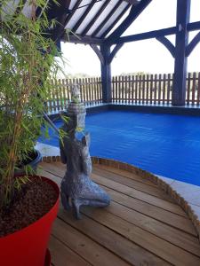 a statue sitting on a deck next to a swimming pool at Domaine des grandes landes in Saint-Paul-la-Roche