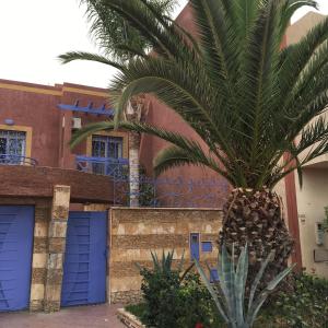 eine Palme vor einem Gebäude mit blauen Türen in der Unterkunft Villa Ory in Agadir