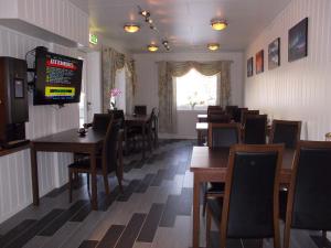 a dining room with tables and chairs and a television at Håkon Gjestehus in Olderdalen