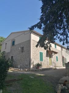 ein großes Steingebäude mit grünen Rollläden in der Unterkunft La Casa dei Nonni in Chianni