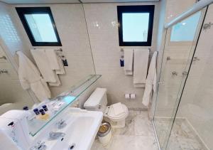 a bathroom with a toilet, sink and mirror at Estanplaza Berrini in São Paulo