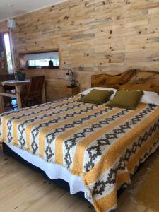 a bedroom with a large bed with a wooden wall at Wau Purul, Cabaña 2 in Cholila