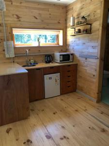 a kitchen in a log cabin with a sink and a microwave at Wau Purul, Cabaña 2 in Cholila