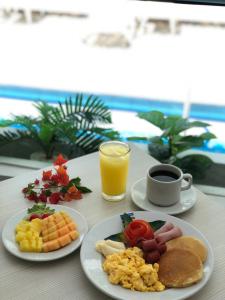 a table with plates of breakfast food and a glass of orange juice at Hotel Be La Sierra in Santa Marta