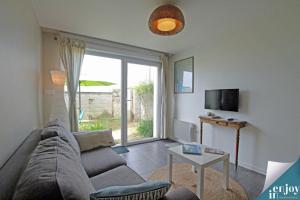 a living room with a couch and a tv at Villa Denise Petit Gîte in Barneville-Carteret