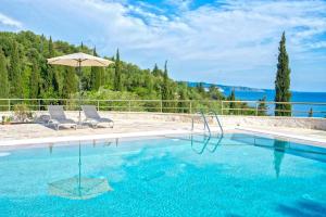 a swimming pool with two chairs and an umbrella at Paleopetres K-Four - Double Suite - Kalami - in Kalami