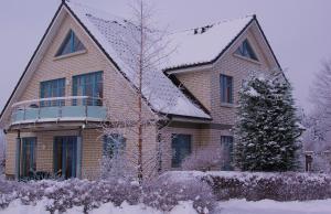 una casa cubierta de nieve con un árbol delante en Haus Carmen auf Usedom Nr.6, en Ziemitz