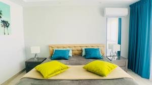 a bedroom with a large bed with yellow and blue pillows at Casa Solaris at Anfi Beach with Private Terrace, Pool & Netflix in Arguineguín +40 photos