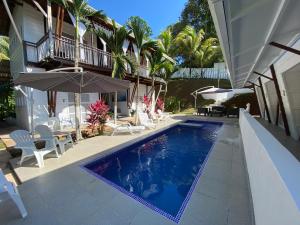 einem Pool mit Stühlen und einem Sonnenschirm neben einem Haus in der Unterkunft Ballena Dorada Lodge in Uvita