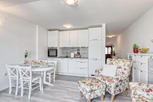 a kitchen with white cabinets and a table and chairs at Penthouse Zola with private parking in Medulin