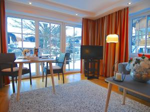 a living room with a dining table and a television at Hubertus Apartments in Schliersee