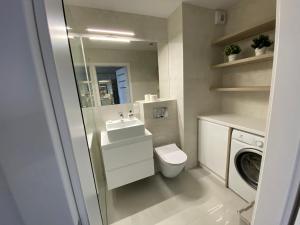 bagno con servizi igienici, lavandino e lavatrice di Flat4You II a Poznań