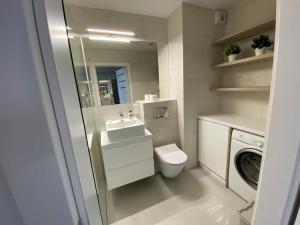 a bathroom with a toilet and a sink and a washing machine at Flat4You II in Poznań