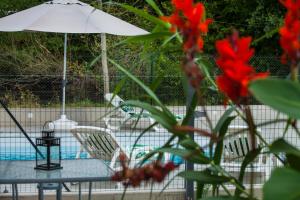 una mesa y sillas junto a una piscina con flores rojas en Ô jardin de boutancourt, en Boutancourt