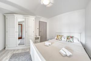 a white bedroom with a large bed and a mirror at Penthouse Zola with private parking in Medulin