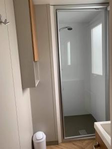 La salle de bains est pourvue d'une douche avec une porte en verre. dans l'établissement VAM Mobil Home Mar Estang, à Canet