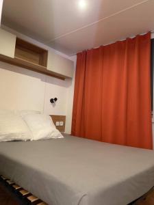 - une chambre avec un lit et un rideau rouge dans l'établissement VAM Mobil Home Mar Estang, à Canet