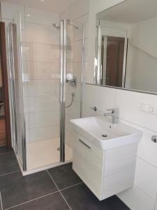a white bathroom with a shower and a sink at Ferienwohnung Stillleben in Ofterschwang