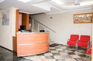 un vestíbulo con 2 sillas rojas y un mostrador en Lelis Hotel, en Itapira