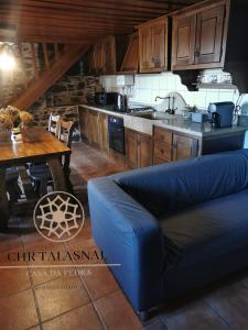 a kitchen with a blue couch and a table in a room at CHR Talasnal_Casa da Pedra in Lousã