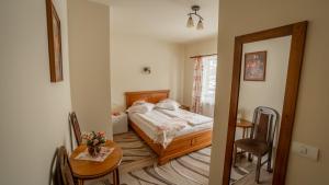 a small bedroom with a bed and a table and a table sidx sidx at Pensiunea Ana in Cavnic +120 photos