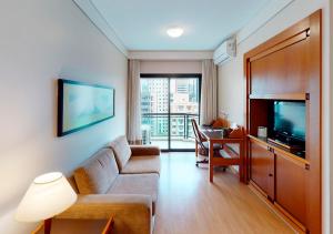 a living room with a couch and a tv and a desk at Estanplaza Nações Unidas in Sao Paulo